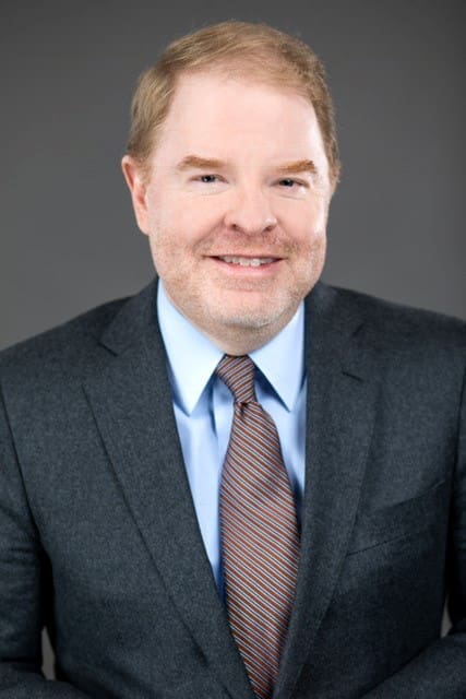 Peter Hans, smiling in a suit and tie