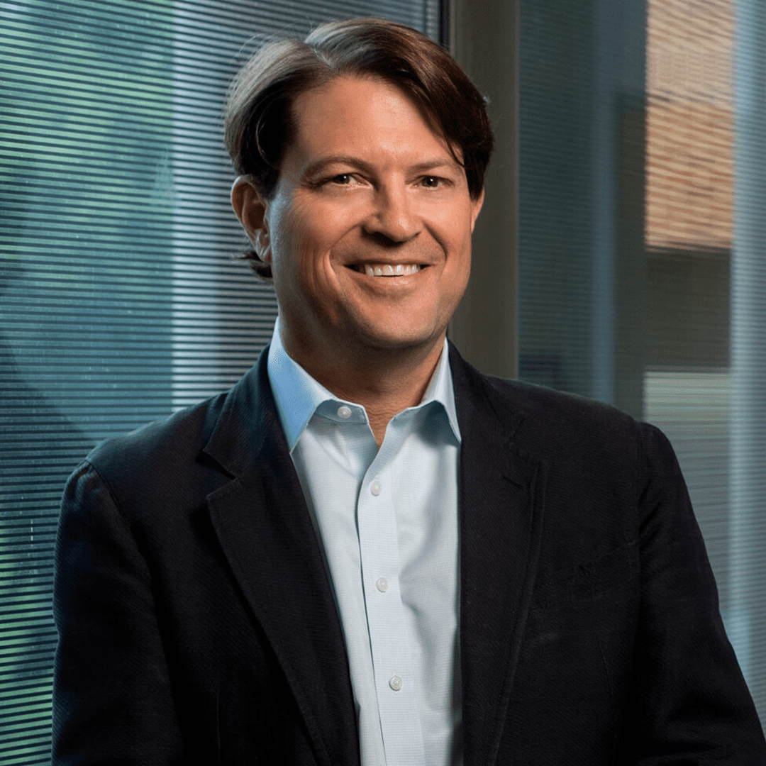 Dr. Jeffrey Stringer, smiling and leaning against a wall of windows.