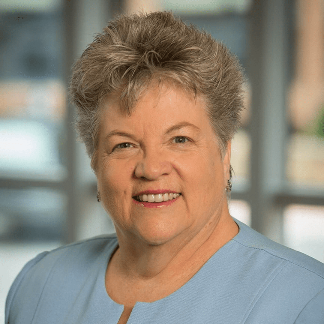 Dr. Carol Durham, smiling with a wall of windows behind her