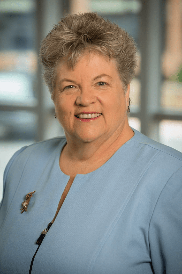 Dr. Carol Durham, smiling with a wall of windows behind her