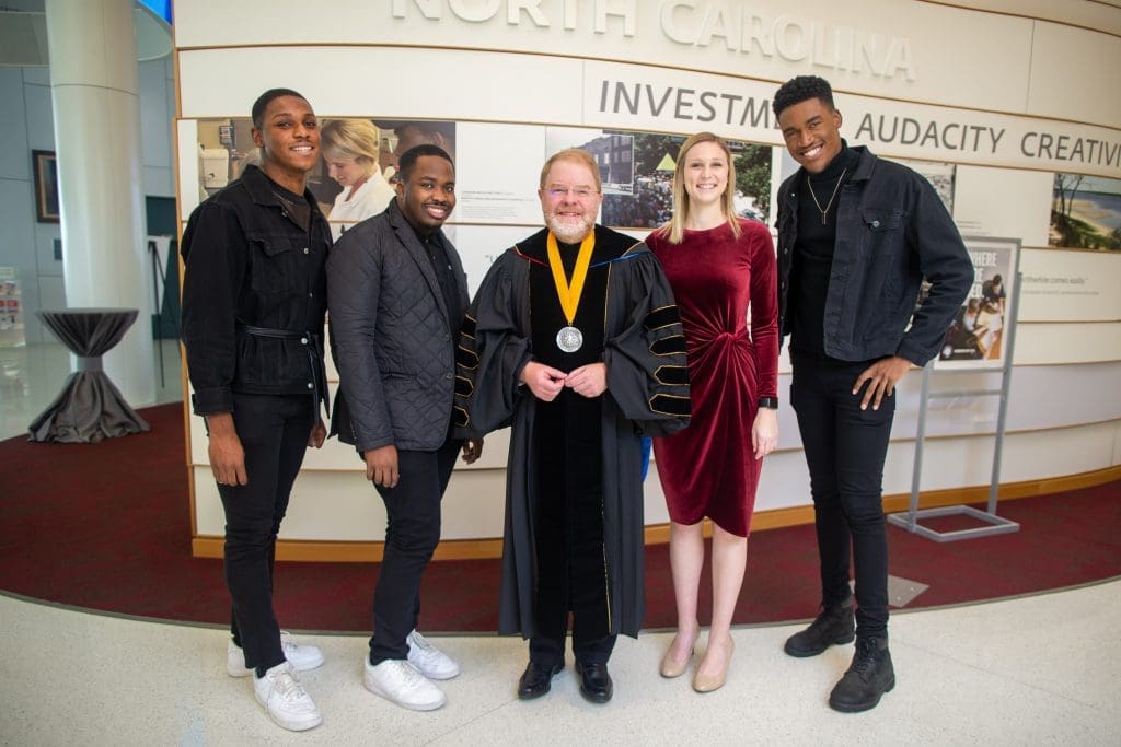 President Hans wearing commencement attire, posing in a group